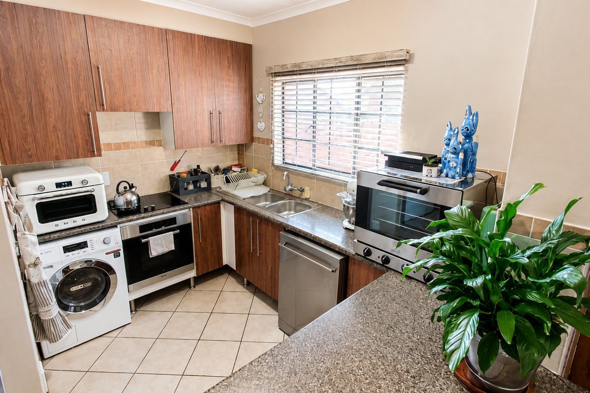 A functional kitchen featuring wood-look cabinetry, granite-style countertops, tiled flooring, and integrated appliance spaces, offering a practical layout for daily meal preparation.