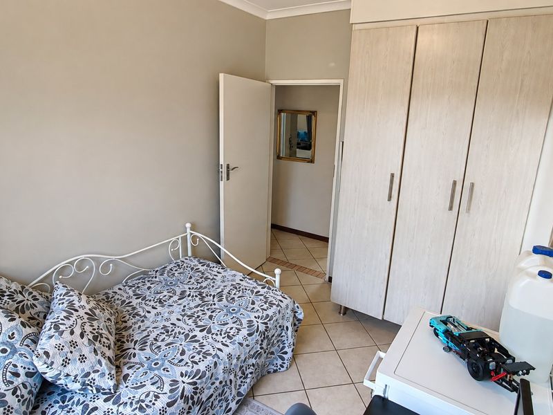 A functional bedroom featuring built-in cupboards, neutral wall finishes, and tiled flooring, providing a clean and practical living space.
