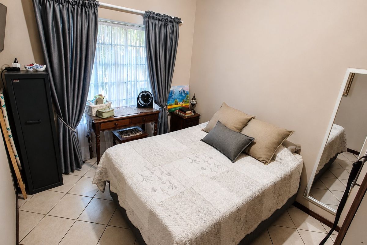A functional bedroom featuring tiled flooring and a window with curtain rails, providing a neutral space ready for personalization.