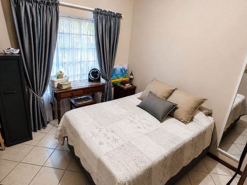 A functional bedroom featuring tiled flooring and a window with curtain rails, providing a neutral space ready for personalization.
