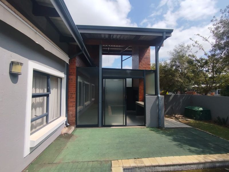 Covered patio area featuring a built-in braai, sliding glass doors, and direct access to the pool area.