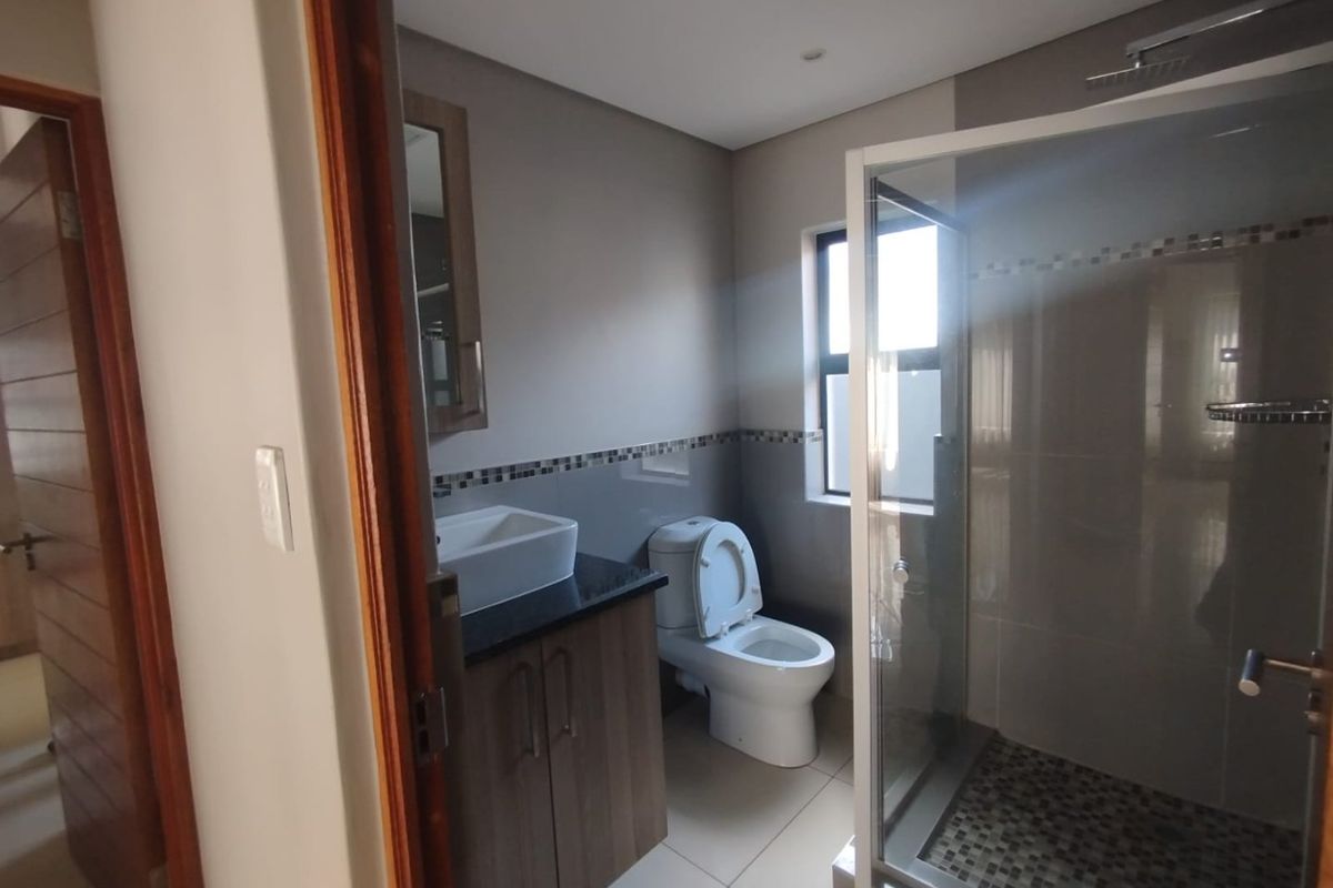Modern bathroom featuring a vanity with vessel sink, granite countertop, and a glass-enclosed shower with tiled accents.
