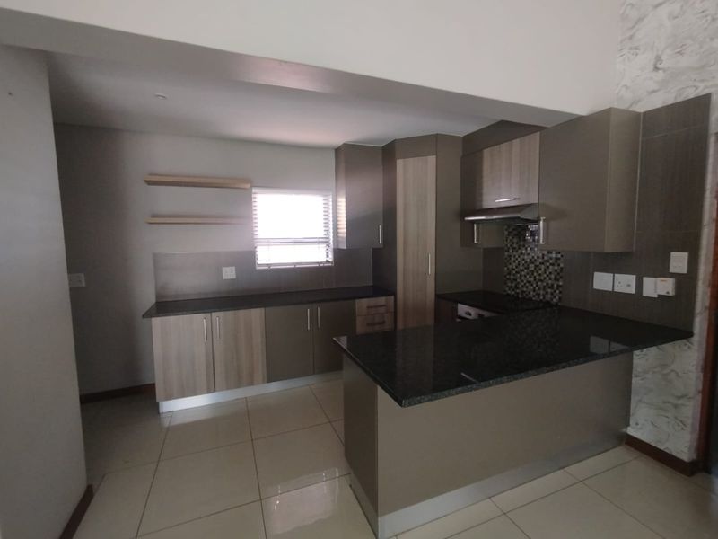 Modern kitchen featuring granite countertops, ample built-in cabinetry, a mosaic tile backsplash, and tiled flooring in an open-plan layout.