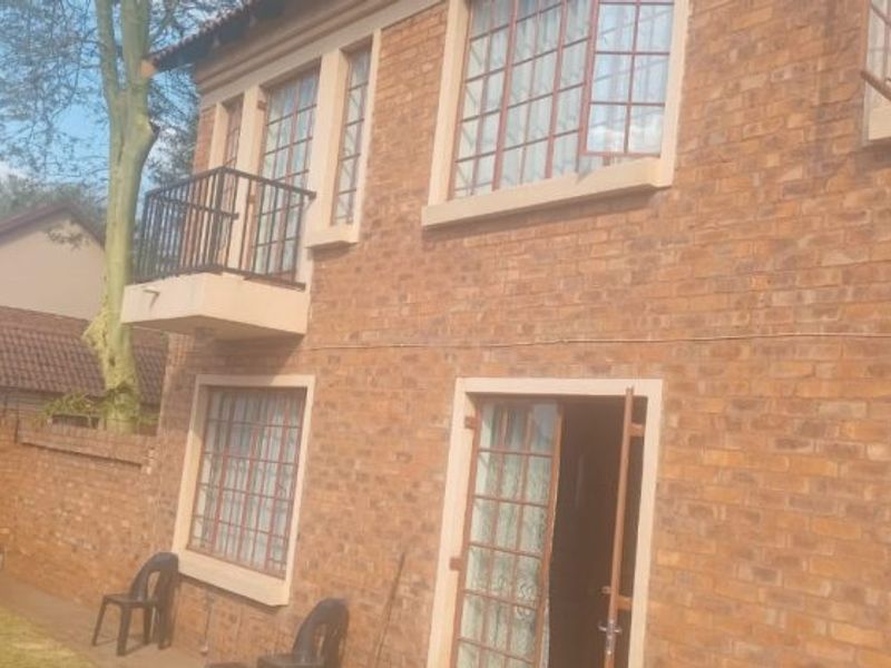 Rear view of a double-story face brick house featuring a small balcony with metal railing and secure steel-framed windows.