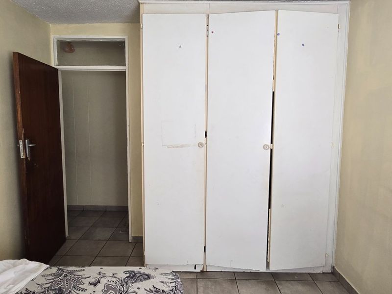 Bedroom featuring tiled flooring, built-in cupboards, and an internal door leading to an adjacent space.
