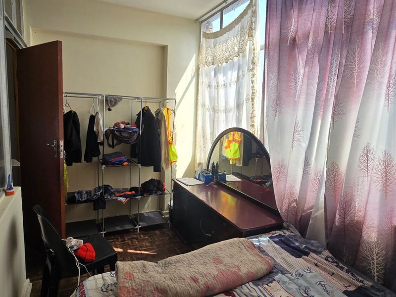 A bedroom featuring large windows that provide ample natural light and classic parquet flooring.