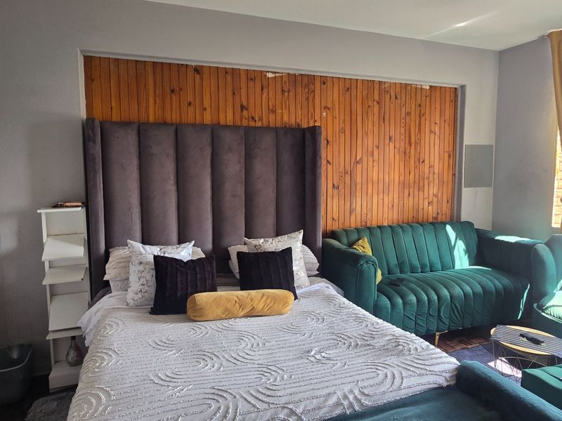 A bedroom featuring timber wall paneling and a built-in cupboard, offering a functional space with potential for aesthetic updates.