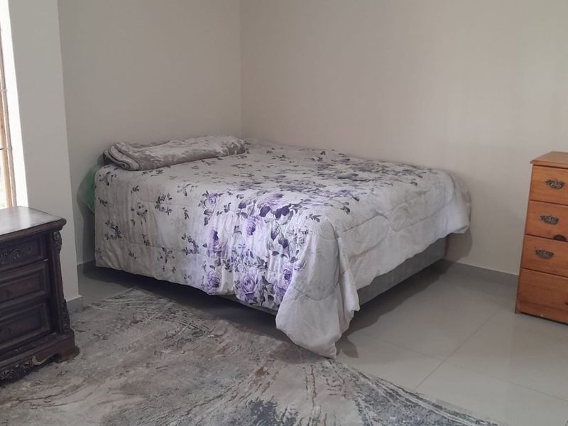 A simple bedroom featuring neutral walls, tiled flooring, and coved ceiling details.