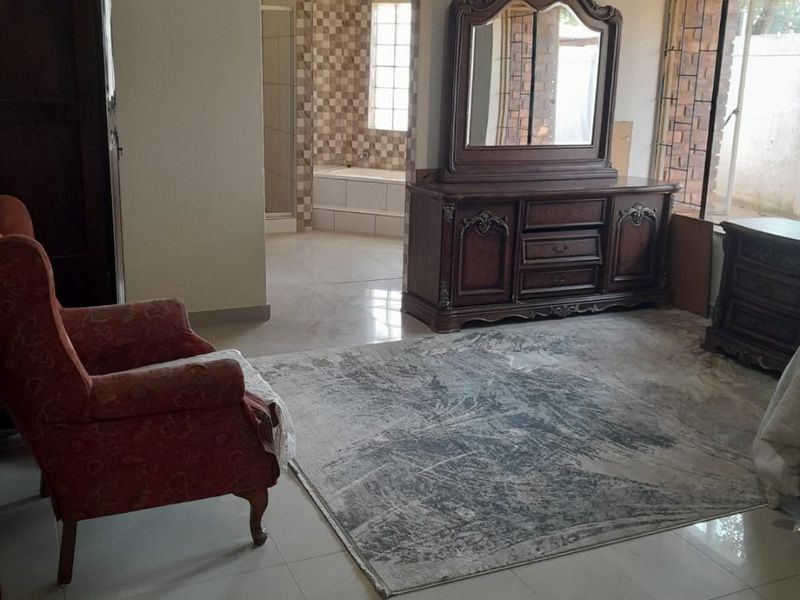Spacious bedroom featuring tiled flooring and direct access to an en-suite bathroom with a bathtub.