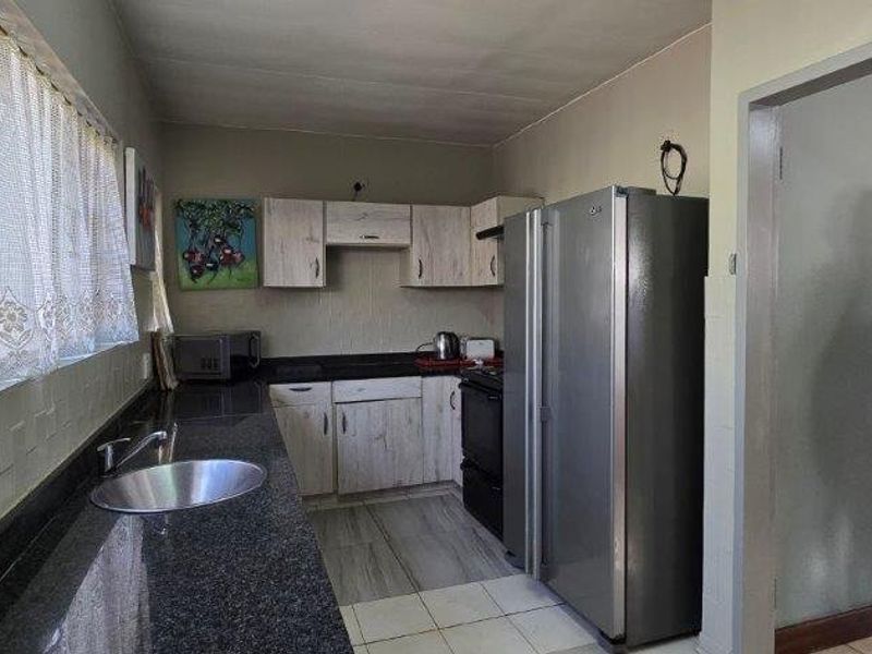 A functional kitchen featuring granite countertops, built-in cabinetry, and tiled flooring, offering a practical layout for daily meal preparation.