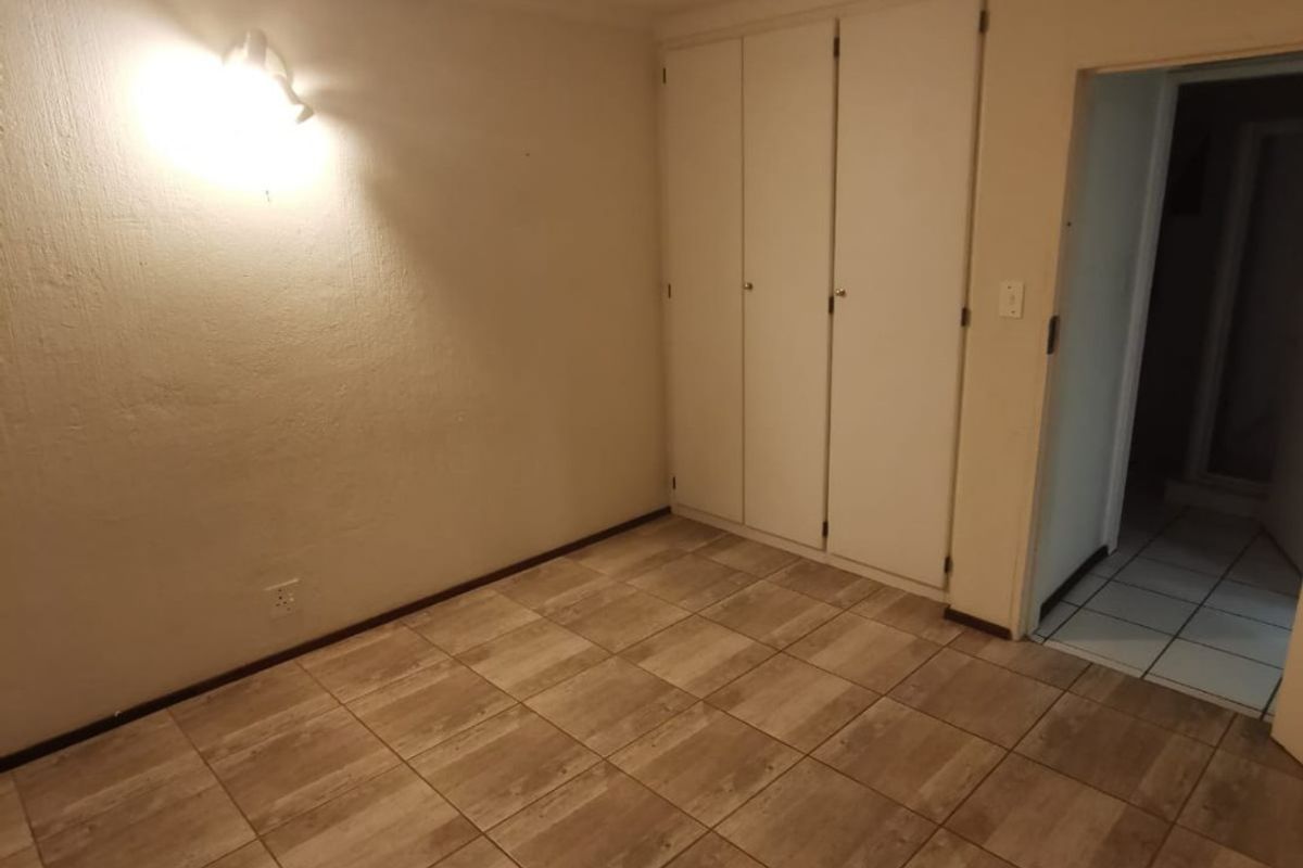 An empty bedroom featuring tiled flooring and built-in cupboards, offering a clean and neutral space ready for personalization.