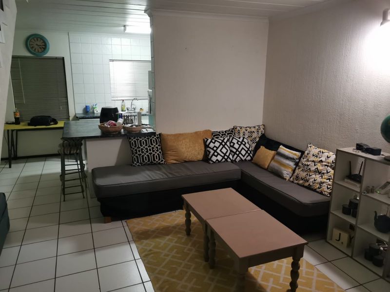 Open plan living area featuring a kitchen with a breakfast bar and tiled flooring throughout, creating a functional and connected living space.