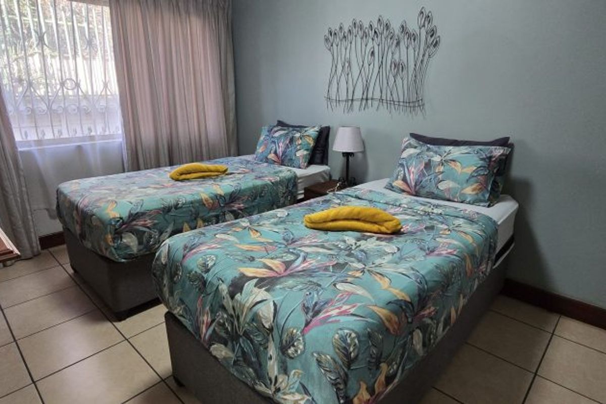 A functional bedroom featuring tiled flooring and a window fitted with security bars, providing a practical and secure living space.