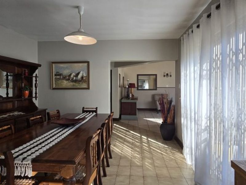 A spacious dining room featuring tiled flooring, a pendant light fixture, and large sliding glass doors that provide access to the outdoor area.