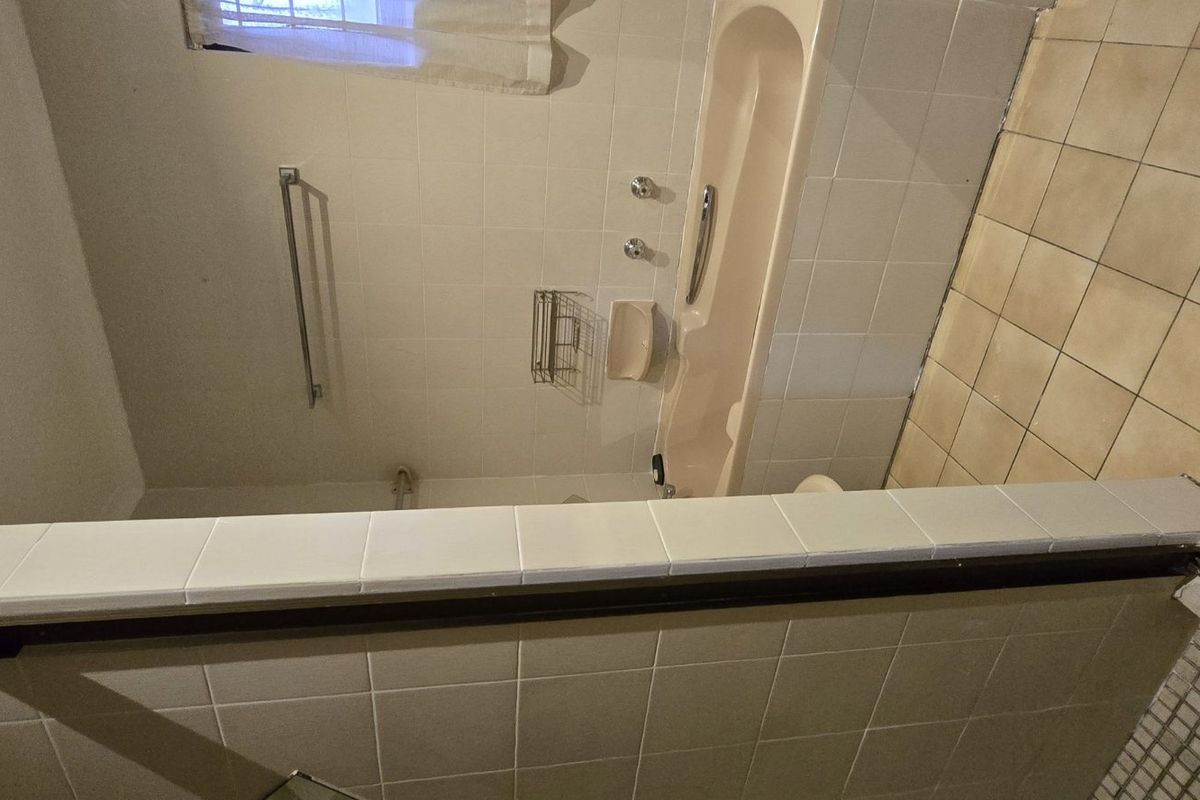 A dated bathroom featuring a bathtub, separate shower enclosure, and neutral ceramic tiling throughout. The space is ready for a modern renovation.