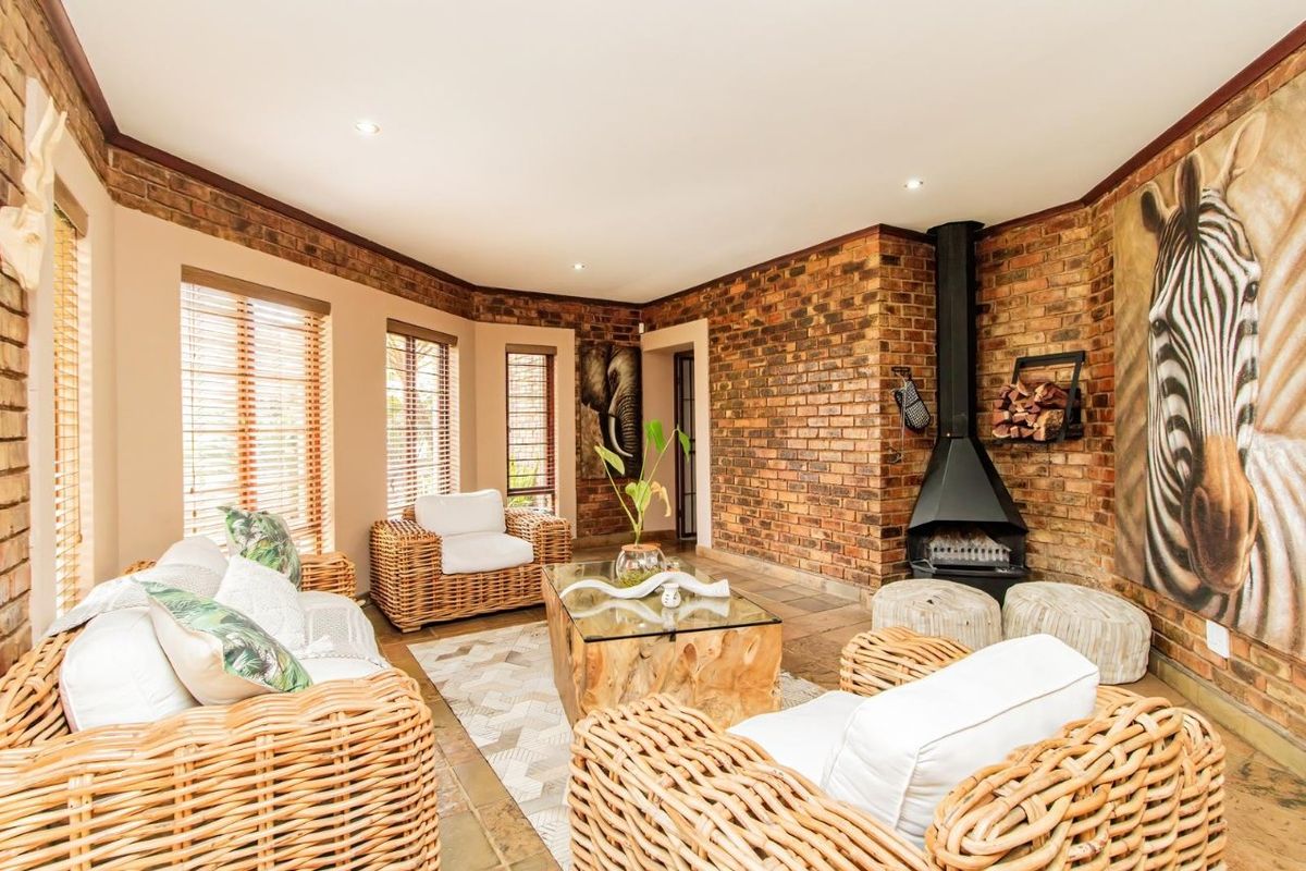 A cozy living room featuring exposed brick walls, stone tile flooring, and a prominent freestanding fireplace, creating a warm and inviting atmosphere.