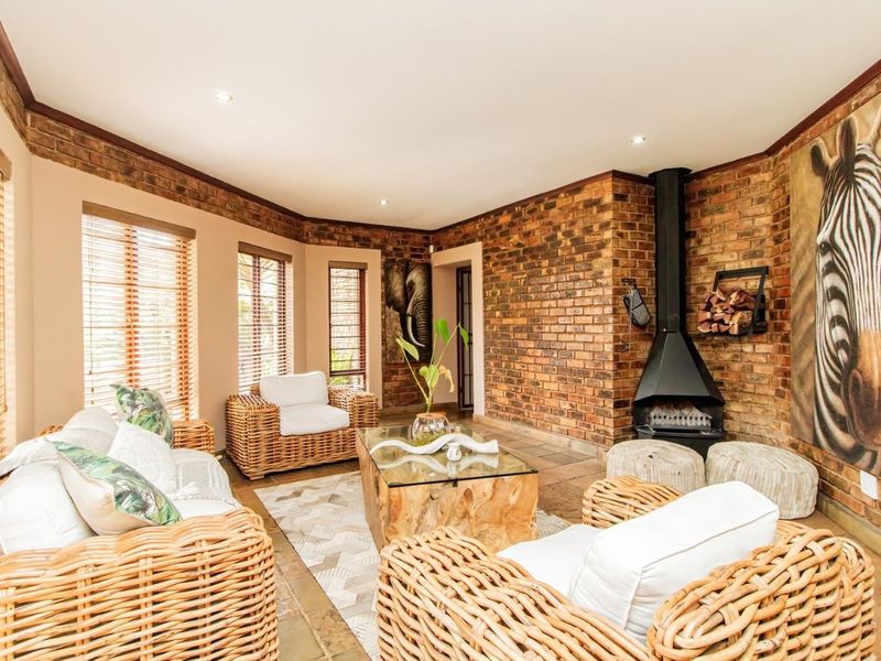 A cozy living room featuring exposed brick walls, stone tile flooring, and a prominent freestanding fireplace, creating a warm and inviting atmosphere.