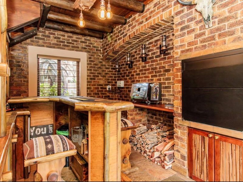 Rustic-style indoor bar area featuring exposed brick walls, timber ceiling beams, a built-in fireplace, and custom wooden bar counter.
