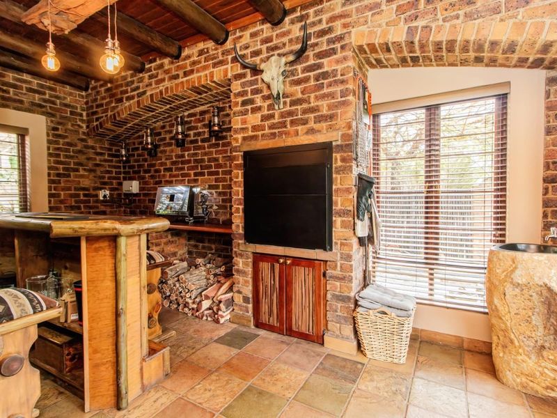 A rustic-style bar area featuring exposed brickwork, a timber beam ceiling, a built-in fireplace, and a unique stone basin.