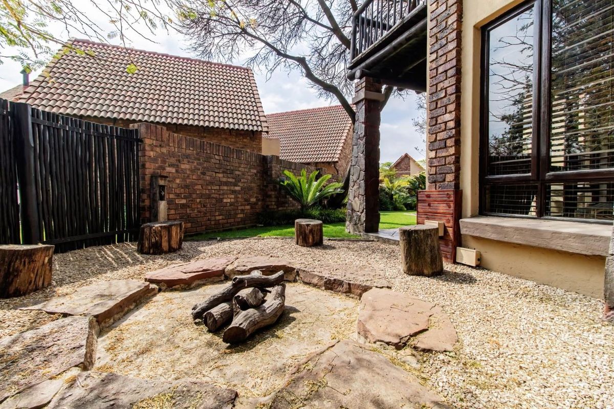 A private rear garden area featuring a stone fire pit, gravel landscaping, and a brick boundary wall, adjacent to the main house structure.