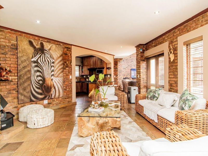 Spacious open-plan living area featuring rustic exposed brick walls, tiled flooring, and a cozy wood-burning fireplace, seamlessly connecting to the kitchen space.