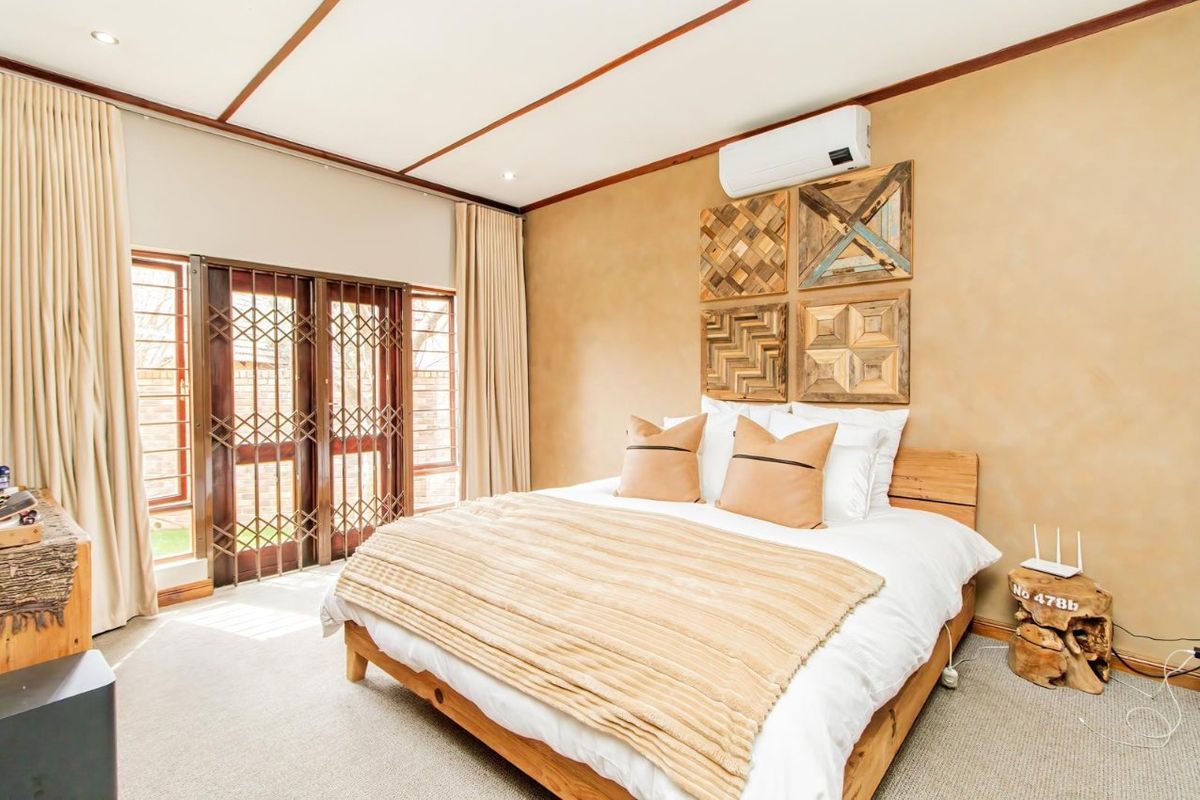 A well-maintained bedroom featuring neutral wall finishes, carpeted flooring, a split-system air conditioner, and sliding glass doors with integrated security gates.