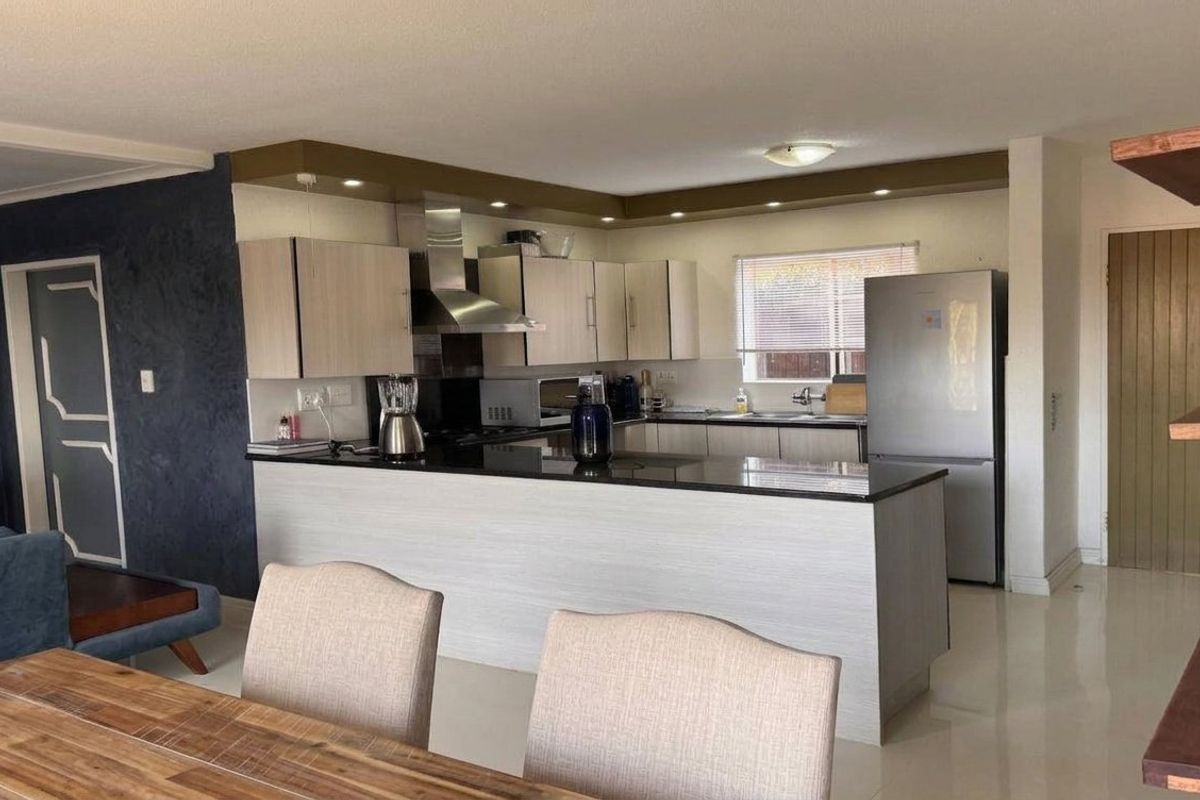 Open-plan kitchen featuring modern cabinetry, granite countertops, and a breakfast bar, seamlessly integrated with the dining and living areas.