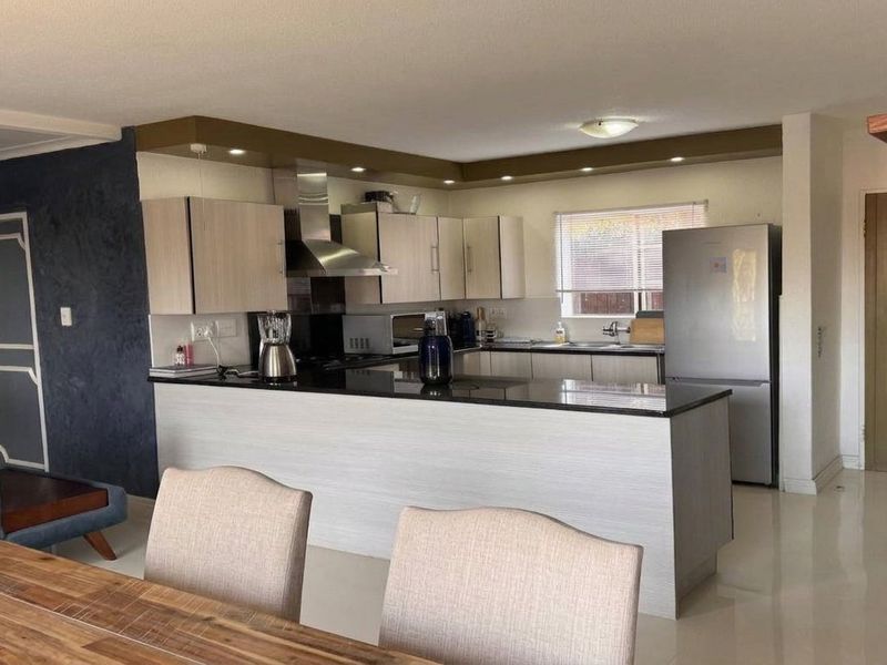 Open-plan kitchen featuring modern cabinetry, granite countertops, and a breakfast bar, seamlessly integrated with the dining and living areas.