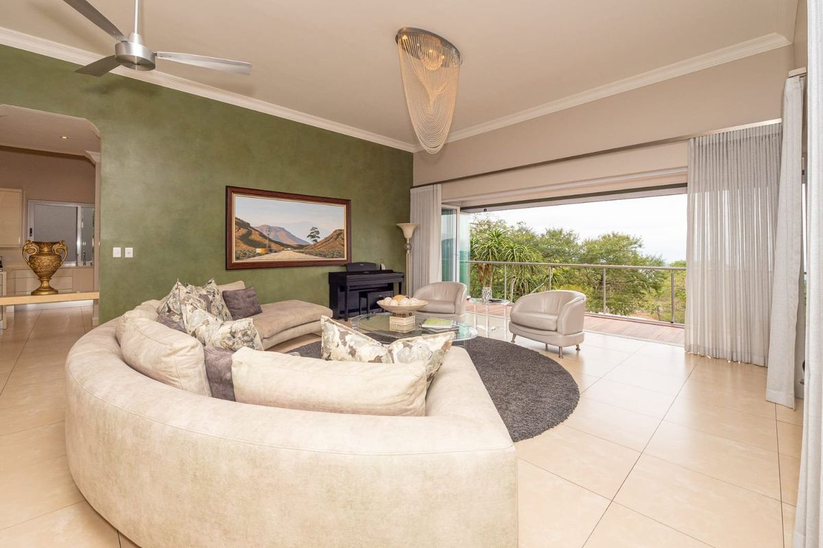 Spacious living room featuring large stacking glass doors that open onto a balcony, tiled flooring, and a modern ceiling fan.