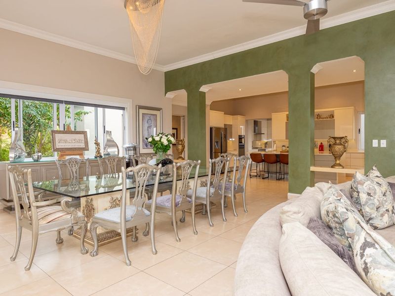 Spacious open-plan living and dining area featuring tiled floors, elegant archways, and seamless flow into a modern kitchen with a central island.