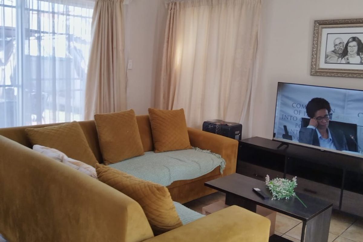 A comfortable living room featuring tiled flooring and natural light from a large sliding glass door.