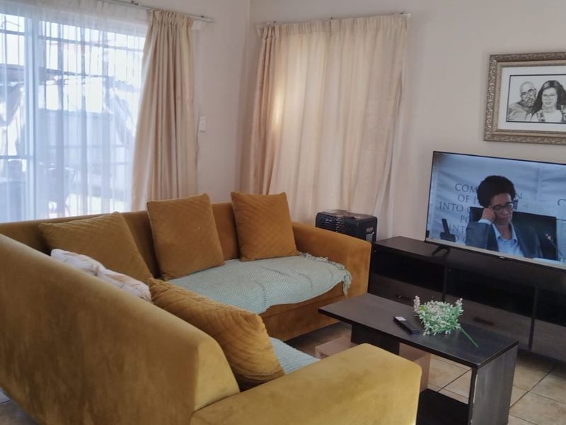 A comfortable living room featuring tiled flooring and natural light from a large sliding glass door.