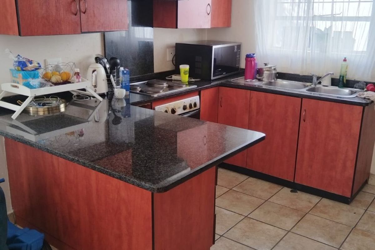 Functional kitchen featuring laminate cabinetry, granite countertops, a double basin sink, and built-in cooking appliances with tiled flooring.