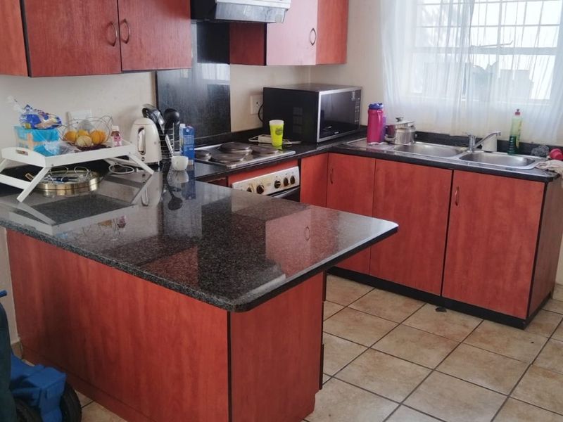 Functional kitchen featuring laminate cabinetry, granite countertops, a double basin sink, and built-in cooking appliances with tiled flooring.