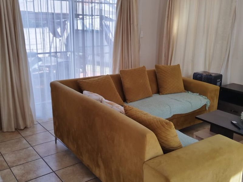 A living room featuring ceramic tiled flooring and a large sliding glass door providing access to the outdoor area.