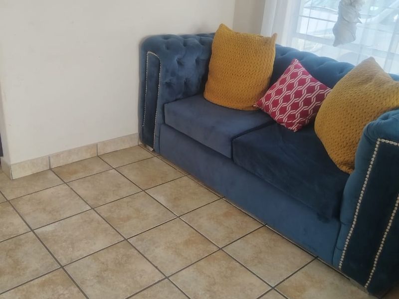 A living room area featuring neutral ceramic floor tiles and matching tiled skirting, providing a clean and functional base for the space.