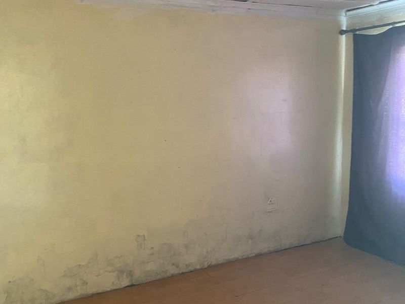 An empty bedroom featuring laminate flooring and a ceiling with visible wear, requiring cosmetic updates and repairs to the wall and ceiling finishes.