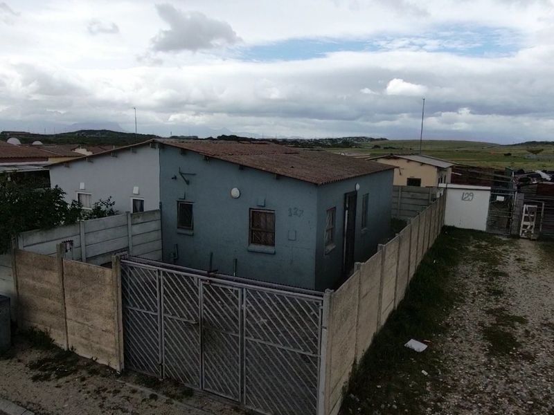 A detached single-story house featuring a tiled roof, security bars on windows, and a fully enclosed yard with a metal security gate.