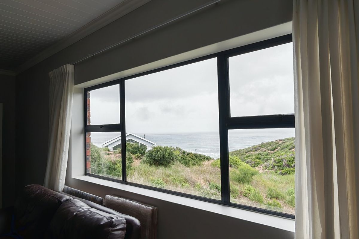 A living room featuring a large picture window that offers expansive coastal and landscape views.