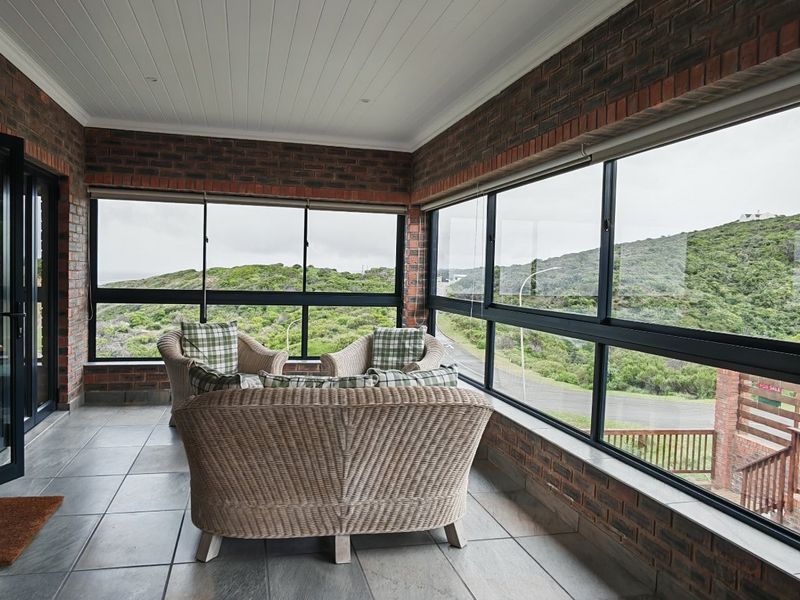 Enclosed patio featuring exposed brick walls, tiled flooring, and large windows offering scenic landscape views, accessible via modern bi-fold doors.