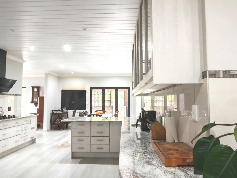 Spacious open-plan kitchen featuring a central island, granite countertops, built-in appliances, and modern finishes, flowing seamlessly into the living and dining areas.