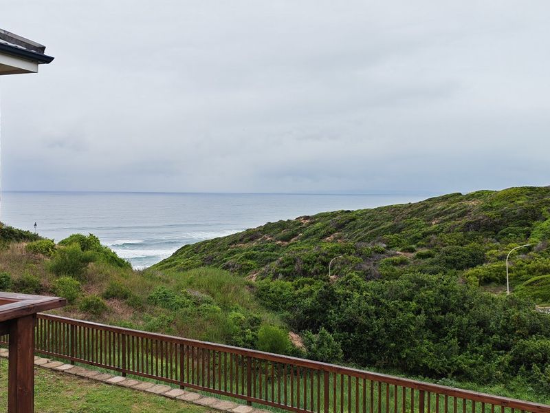 A scenic elevated view overlooking the coastal landscape, featuring a brick exterior wall and timber balcony railing.