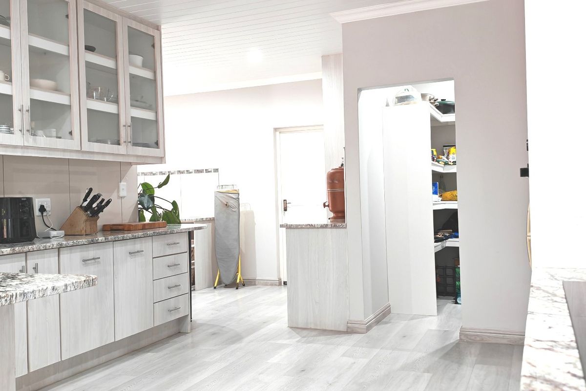 Modern kitchen featuring light wood-grain cabinetry, granite countertops, a gas hob, and a convenient walk-in pantry with ample storage space.