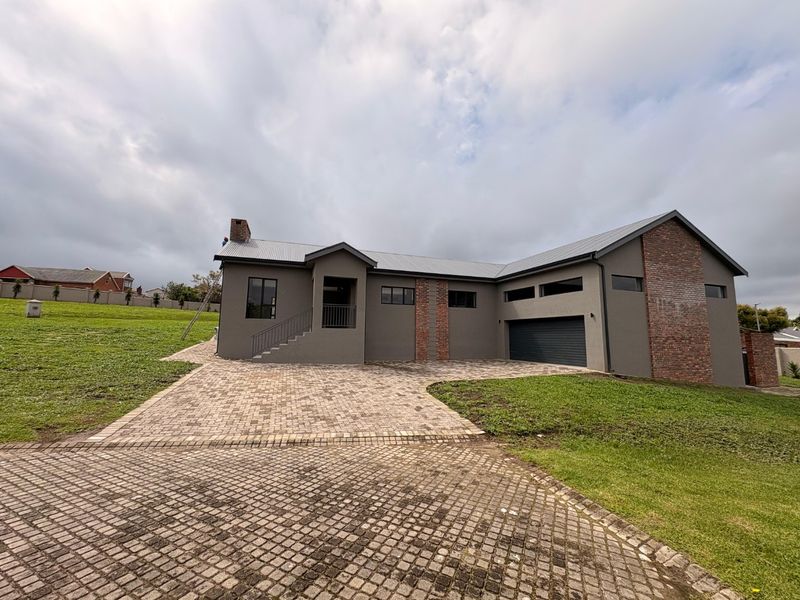 Modern single-story house featuring a paved driveway, double garage, and a combination of rendered walls and brick detailing.