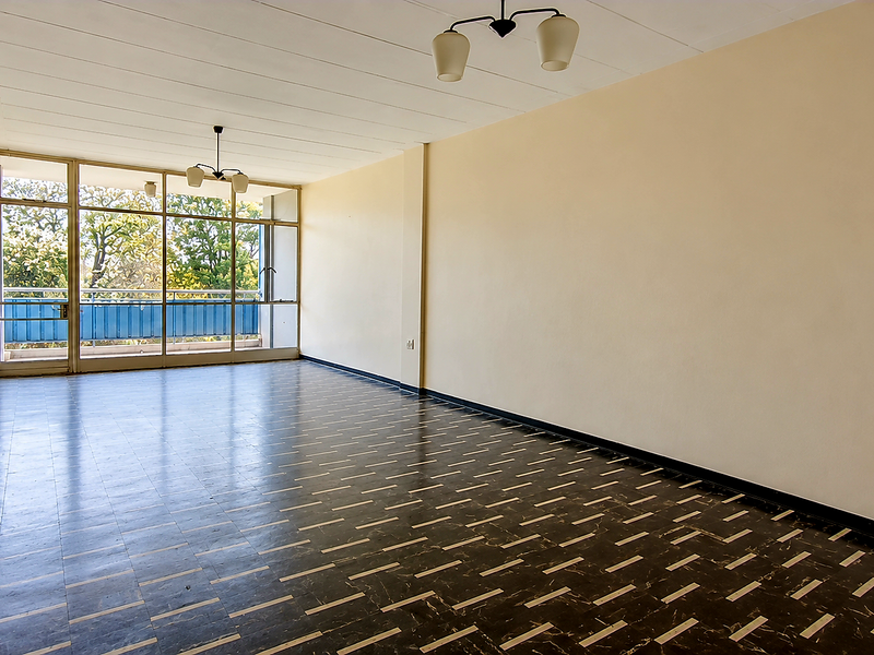 A spacious, empty living area featuring large glass sliding doors that provide natural light and access to an outdoor balcony.