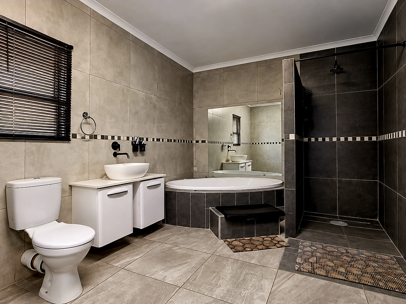 Modern bathroom featuring a walk-in shower, built-in bathtub, wall-mounted basin, and neutral tiled finishes throughout.