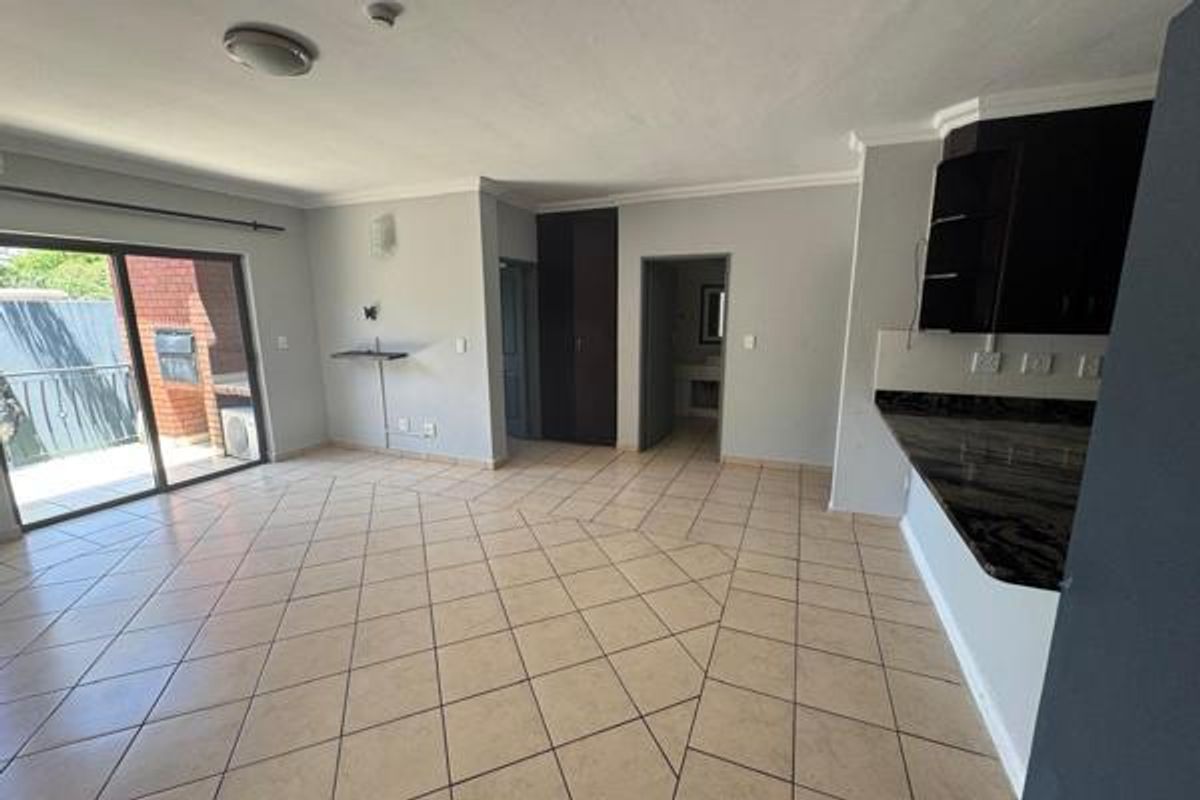 Spacious open-plan living area featuring ceramic tiled flooring, granite kitchen countertops, and sliding door access to a private balcony.
