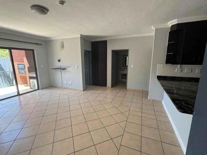 Spacious open-plan living area featuring ceramic tiled flooring, granite kitchen countertops, and sliding door access to a private balcony.