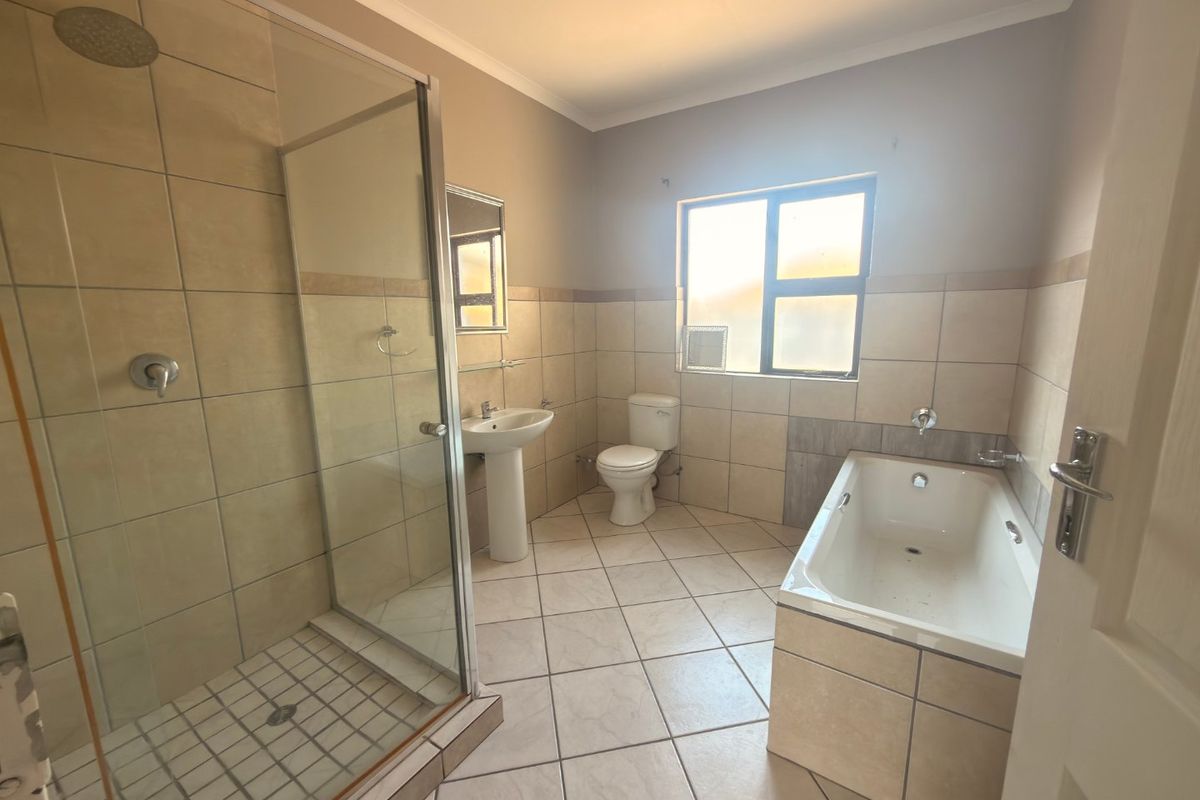 A spacious bathroom featuring a separate shower enclosure, pedestal basin, toilet, and a built-in bathtub with neutral wall and floor tiling.
