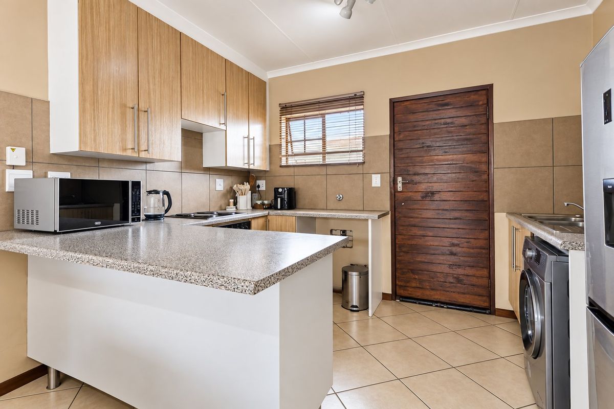 A functional kitchen featuring light wood cabinetry, granite countertops, tiled backsplash, and dedicated plumbing for a washing machine.